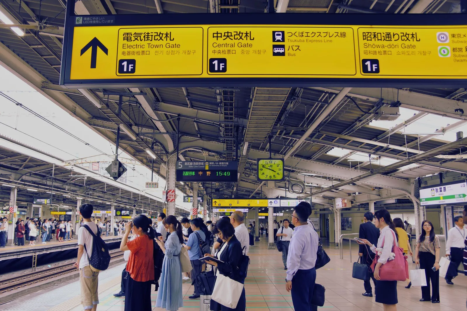 A busy but orderly train platform with clear signage inside a large Japanese railway station