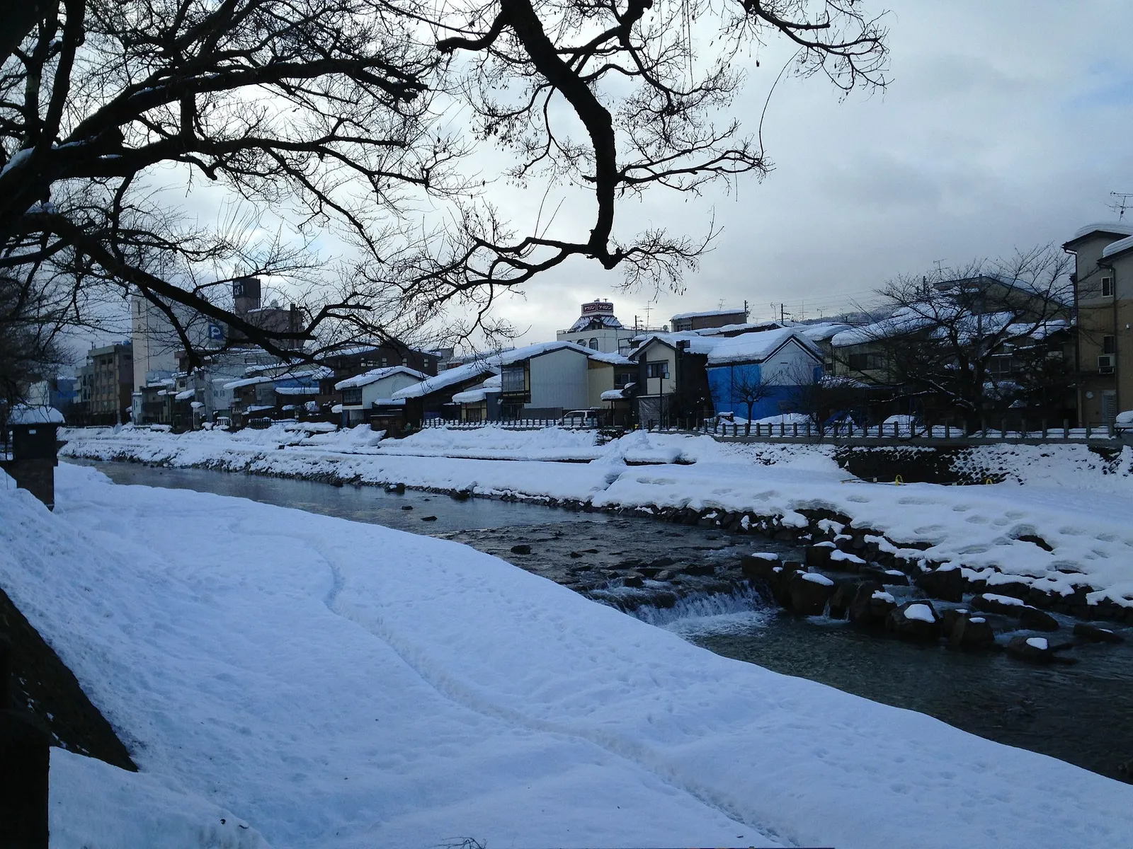 The Miyagawa riverside in Takayama under snow, with the wooden houses of the old town along the bank