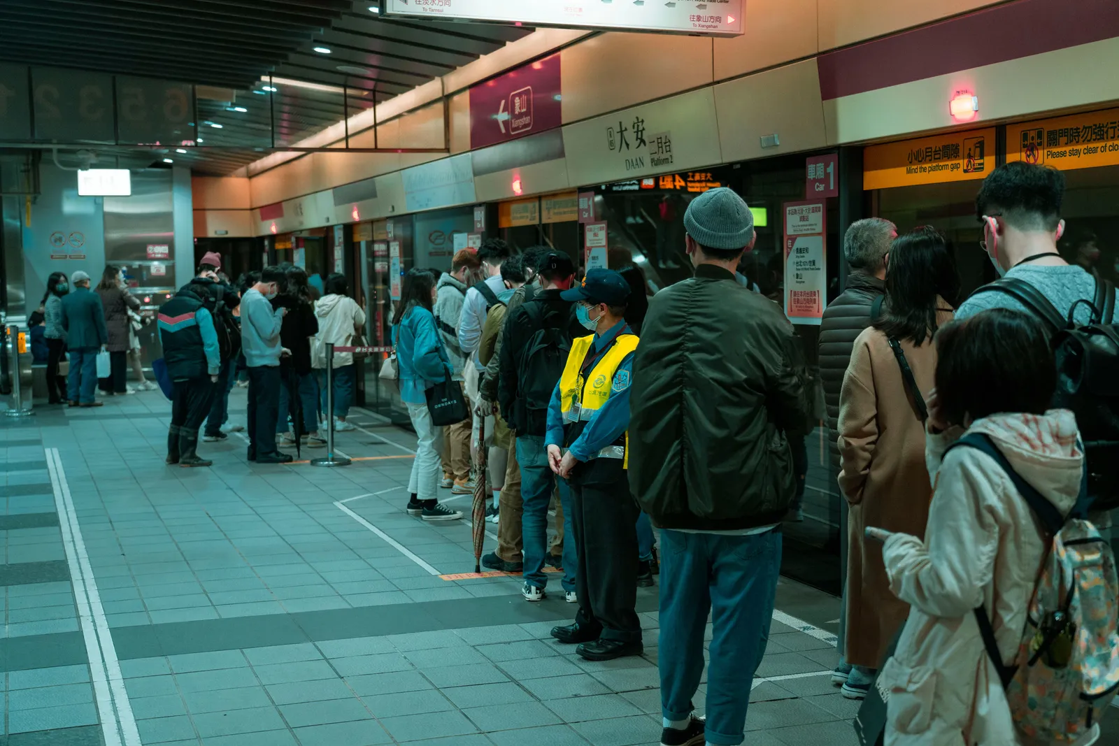 A crowded railway platform in Japan with passengers queueing to board a train