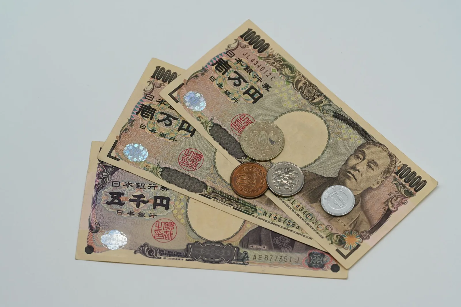 Japanese yen banknotes fanned out with coins resting on them